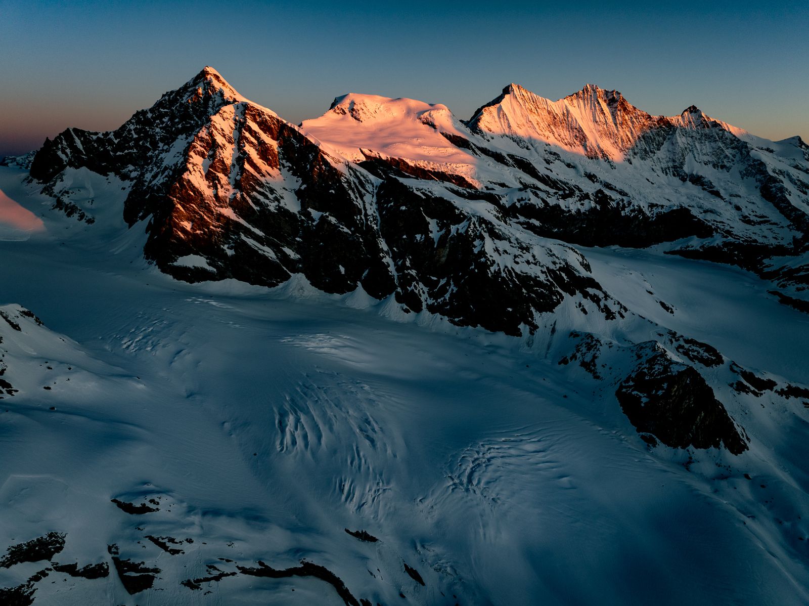 First light on high alpine peaks above a glacier