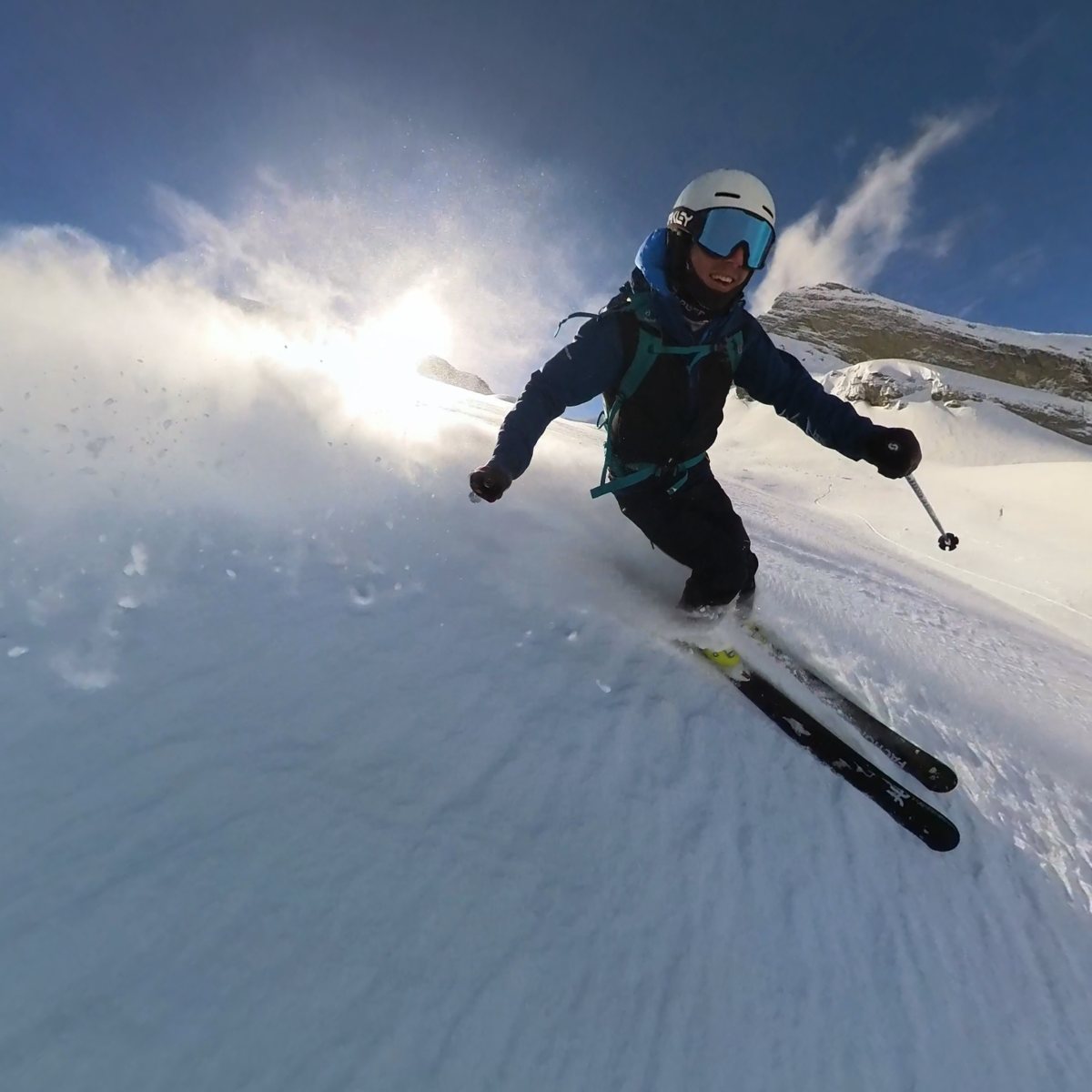 Olly skiing fresh powder with snow spraying in the sunlight