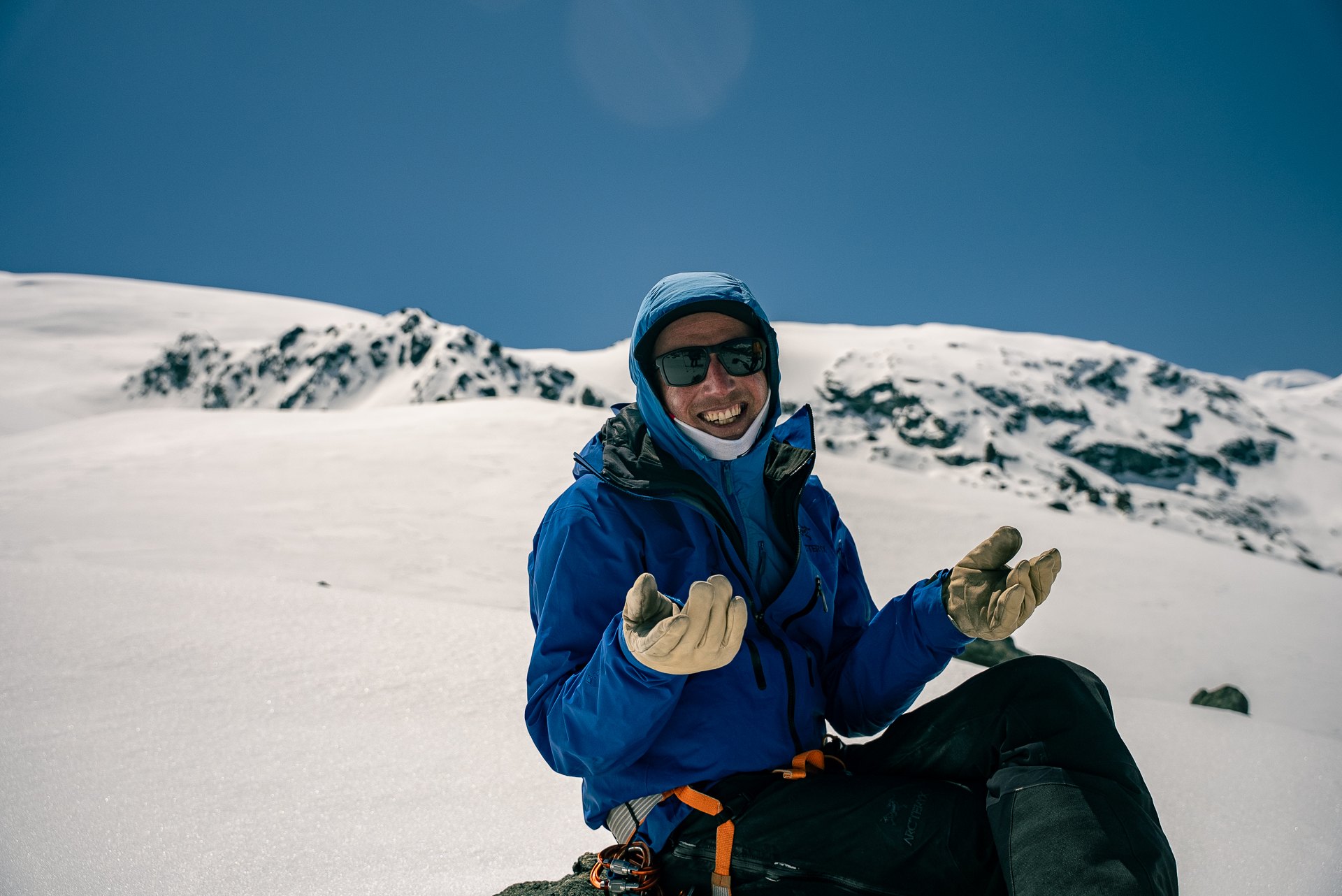 Olly smiling on a snowy mountainside, gloves held out to each side