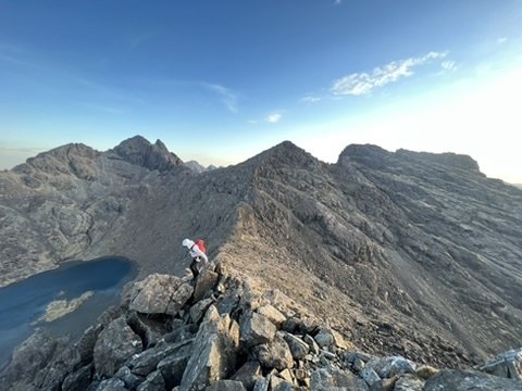 A climber on a rocky Scottish ridge above a mountain loch