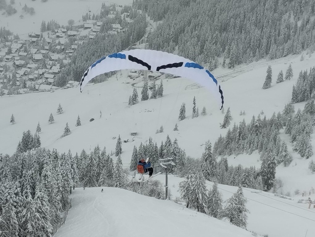 Flying on skis low over snowy forest above Verbier