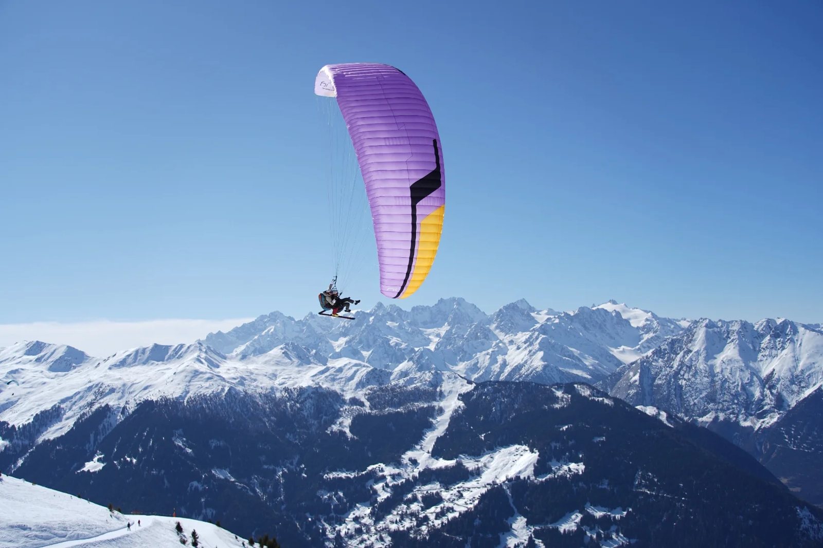 A tandem paraglider flying above Verbier with the Grand Combin massif behind